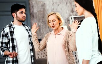 A middle-aged woman raises her hands in frustration between a young man in a plaid shirt and a young woman in a white shirt. They appear to be having a tense discussion in a room with gray walls and yellow curtains.