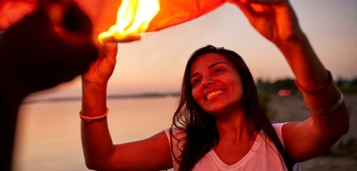 young woman feeling joy as she releases a lantern into the sky