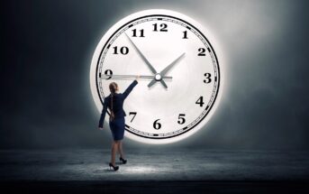 A woman in professional attire stands in front of an oversized clock against a dark background, reaching towards the clock's hands. The clock shows around 10:10. The scene is dramatic and symbolic of time management.