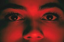 fear of being cheated on - closeup of woman's face illuminated with a red light