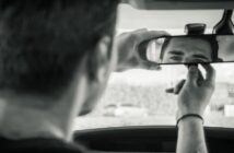 man looking at himself in the rear-view mirror