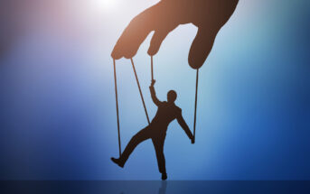 A silhouette of a large hand controlling a silhouetted person with strings, resembling a puppet. The background features a gradient of blue and purple shades, with light shining from the top left corner.