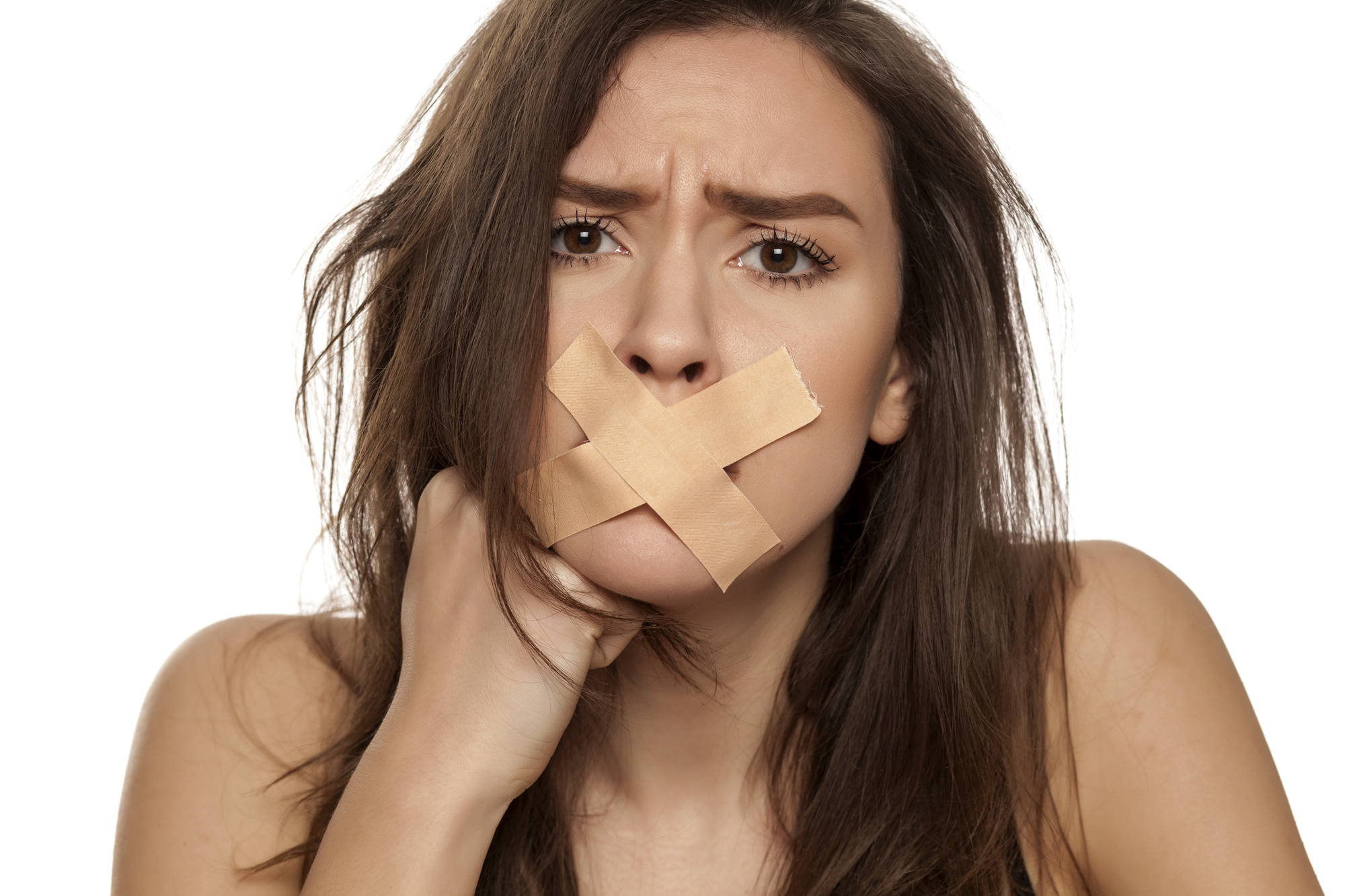 A woman with long brown hair looks directly at the camera with a distressed expression. Two strips of beige tape are crossed over her mouth, suggesting she is silenced. She rests her chin on her hand, and the background is plain white.