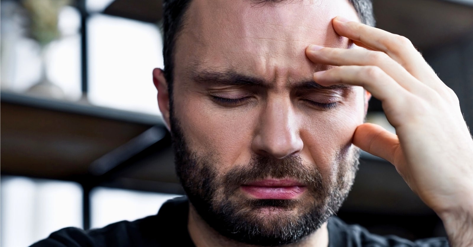man with fingers pressed against his forehead as he struggles with his mental health