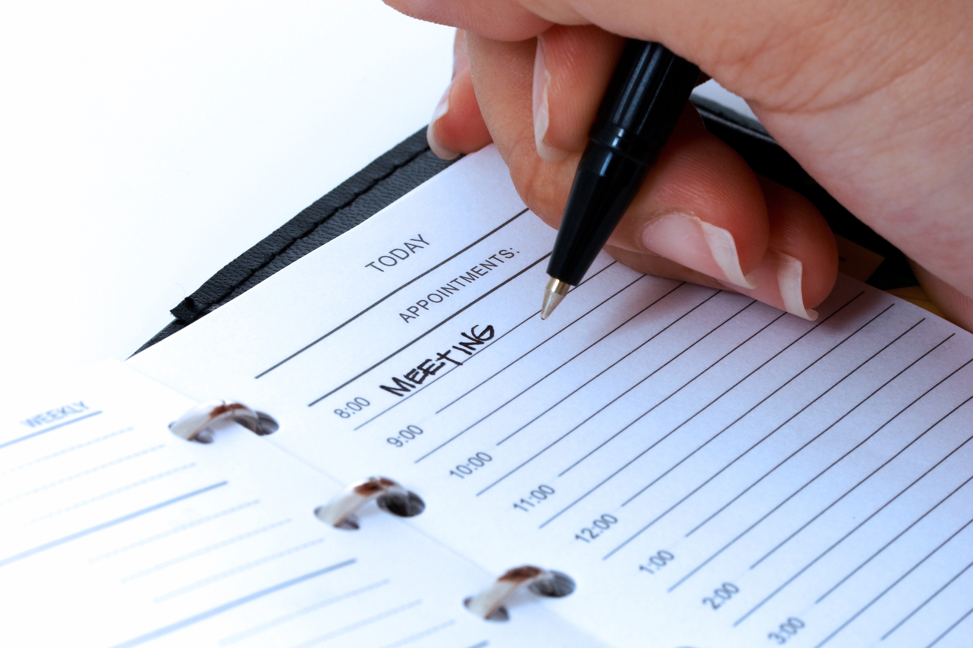 A hand holding a pen writes "MEETING" on an 8 am slot in a planner's "Today" section. The planner has lined slots for appointments, ranging from 8:00 to 12:00.