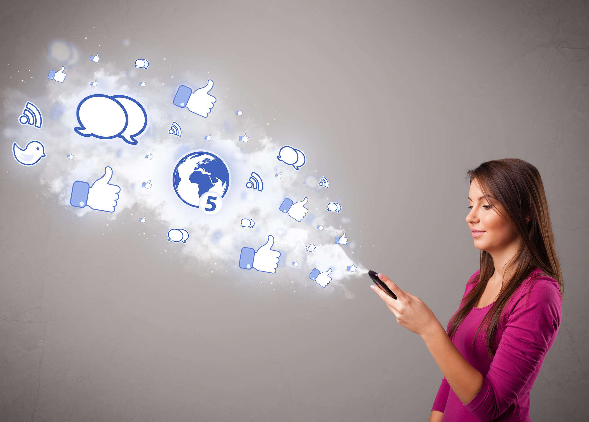 A woman in a purple top holds a smartphone, with various social media icons such as thumbs up, chat bubbles, and a globe emanating from it, symbolizing social media interaction. The background is a plain grey wall.