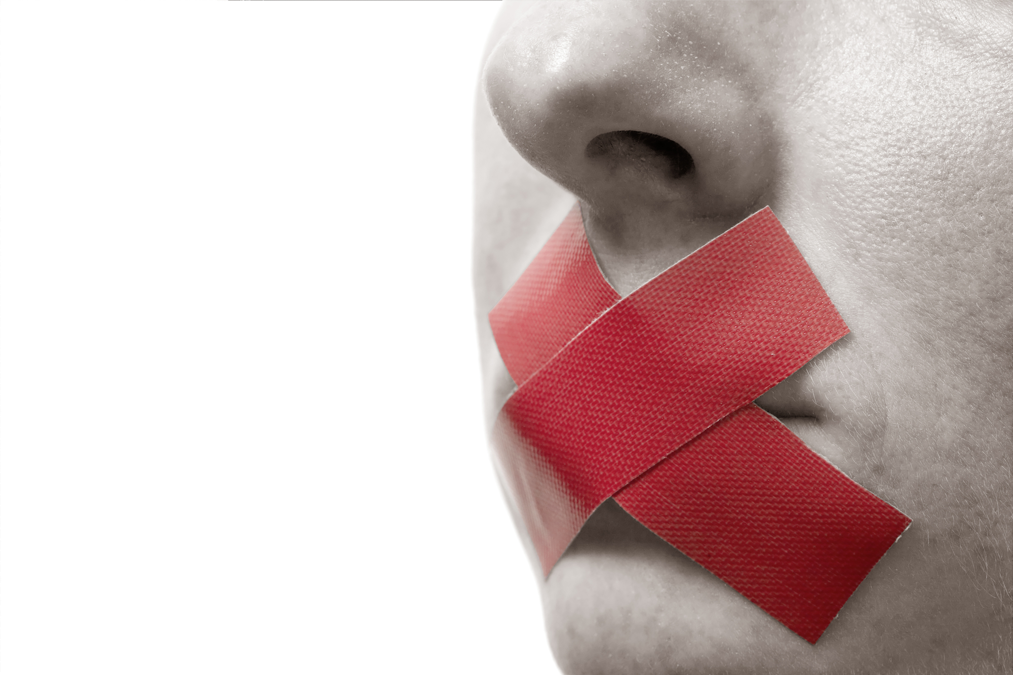 Close-up of a person's face with their mouth covered by two red pieces of tape forming an X. The image focuses on the nose and mouth area, with the rest of the face out of frame. The background is white, emphasizing the red tape on the mouth.