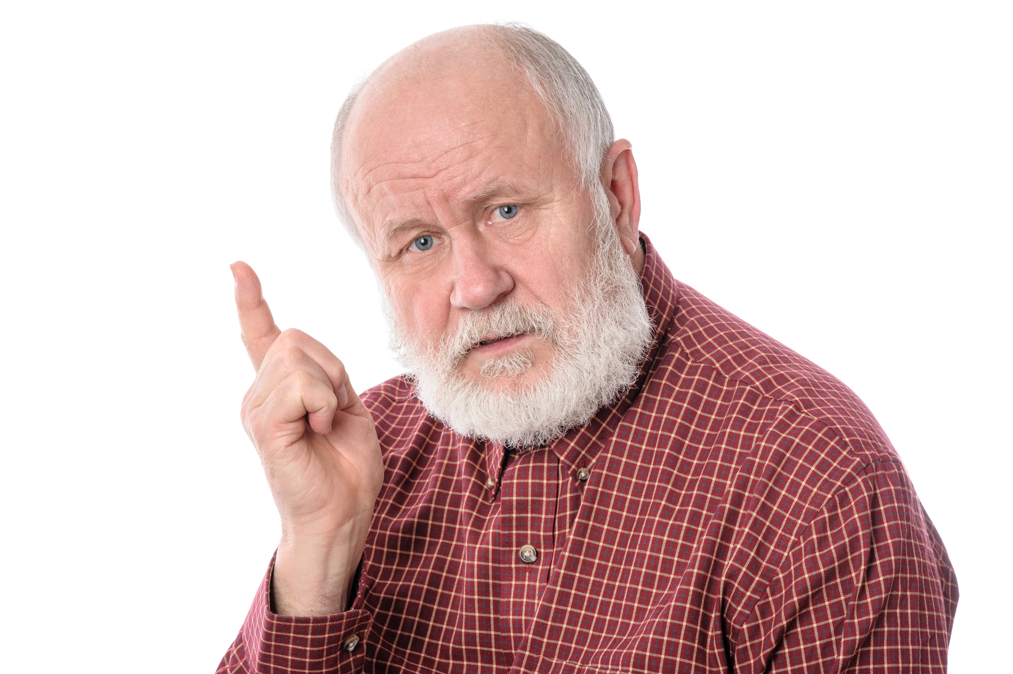 An elderly man with a white beard and thinning hair wearing a red and black checkered shirt stands against a plain white background. He has an expressive face and is holding up his right index finger, as if making a point or giving advice.