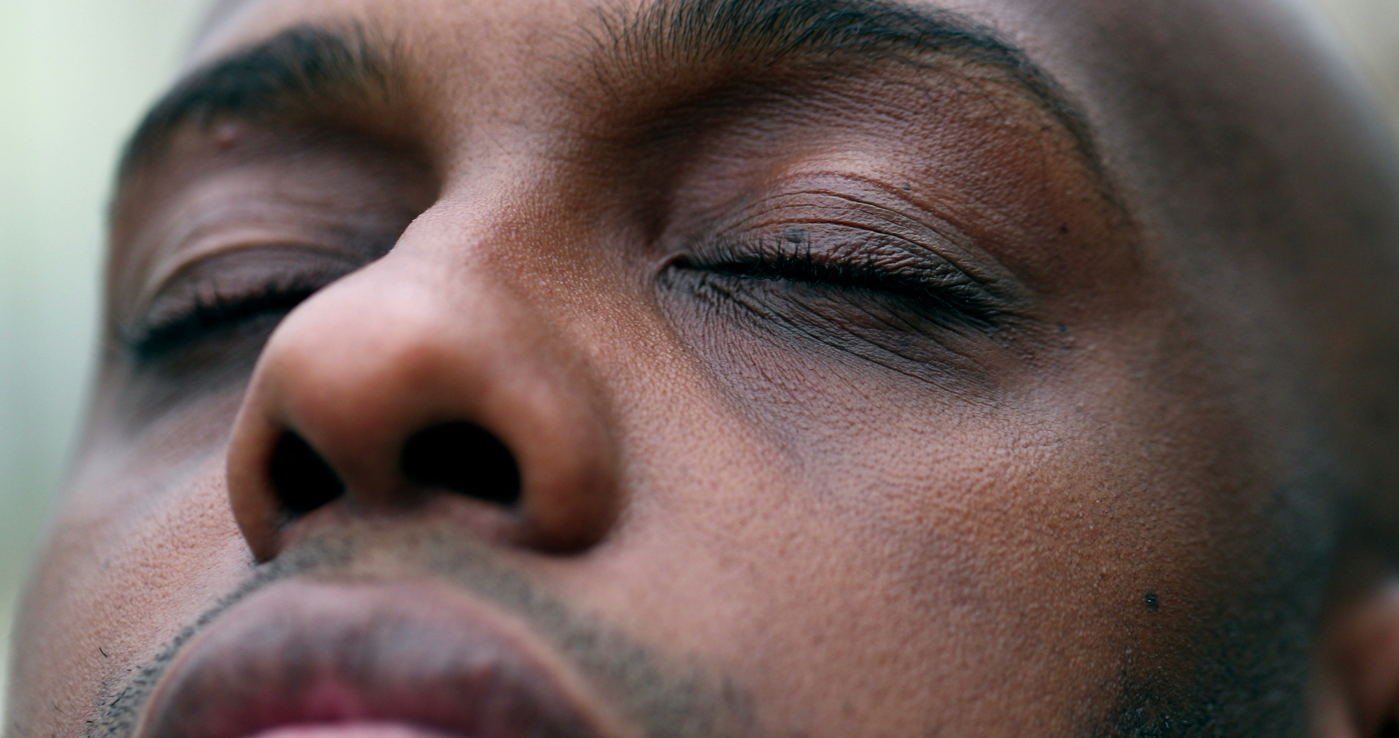 Close-up of a person's face with their eyes closed, showing a serene expression. The individual's skin is smooth, and the image focuses on the eyelids, eyebrows, and the bridge of the nose, highlighting the peaceful and calm demeanor.