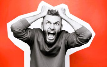 A man with a beard is pulling his hair and yelling, appearing frustrated. He's against a bright orange background with a white abstract shape. He's wearing a casual sweatshirt.