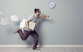 A man with a ponytail, wearing glasses and casual clothes, runs hurriedly while holding a folder and some papers, with a few sheets flying behind him. A clock on the wall shows 10:10. The setting is a minimalistic room with a light-colored floor.